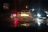 Genangan air menutupi badan jalan  dan tampak pengendara sepeda motor mengalami mesin mogok di tengah jalan