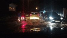 Genangan air menutupi badan jalan  dan tampak pengendara sepeda motor mengalami mesin mogok di tengah jalan