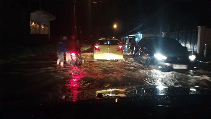 Genangan air menutupi badan jalan  dan tampak pengendara sepeda motor mengalami mesin mogok di tengah jalan