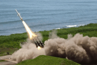 ilustrasi gambar Peluncuran rudal dari kendaraan militer di area pesisir