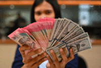 Karyawan memperlihatkan uang pecahan rupiah dan dolar Amerika Serikat (AS) di gerai penukaran mata uang asing Ayu Masagung, Jakarta, Selasa (12/5/2026). Foto: Indrianto Eko Suwarso/ANTARA FOTO