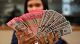 Karyawan memperlihatkan uang pecahan rupiah dan dolar Amerika Serikat (AS) di gerai penukaran mata uang asing Ayu Masagung, Jakarta, Selasa (12/5/2026). Foto: Indrianto Eko Suwarso/ANTARA FOTO