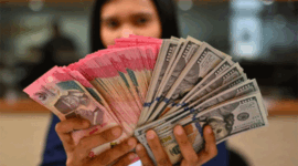 Karyawan memperlihatkan uang pecahan rupiah dan dolar Amerika Serikat (AS) di gerai penukaran mata uang asing Ayu Masagung, Jakarta, Selasa (12/5/2026). Foto: Indrianto Eko Suwarso/ANTARA FOTO