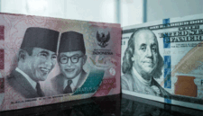 Sejumlah uang kertas pecahan 100.000 rupiah Indonesia difoto di samping uang kertas pecahan 100 dolar AS di sebuah tempat penukaran mata uang di Jakarta, Kamis (4/6/2026). Foto: Yasuyoshi Chiba/AFP