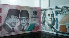 Sejumlah uang kertas pecahan 100.000 rupiah Indonesia difoto di samping uang kertas pecahan 100 dolar AS di sebuah tempat penukaran mata uang di Jakarta, Kamis (4/6/2026). Foto: Yasuyoshi Chiba/AFP