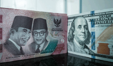 Sejumlah uang kertas pecahan 100.000 rupiah Indonesia difoto di samping uang kertas pecahan 100 dolar AS di sebuah tempat penukaran mata uang di Jakarta, Kamis (4/6/2026). Foto: Yasuyoshi Chiba/AFP
