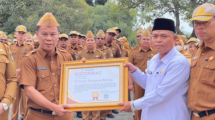 Sekda Alpian menyerahkan sertifikat penghargaan kepada Kantor Urusan Agama (KUA) Kecamatan Hamparan Rawang