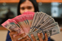 Karyawan memperlihatkan uang pecahan rupiah dan dolar Amerika Serikat (AS) di gerai penukaran mata uang asing Ayu Masagung, Jakarta, Selasa (12/5/2026)