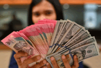 Karyawan memperlihatkan uang pecahan rupiah dan dolar Amerika Serikat (AS) di gerai penukaran mata uang asing Ayu Masagung, Jakarta, Selasa (12/5/2026)