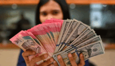 Karyawan memperlihatkan uang pecahan rupiah dan dolar Amerika Serikat (AS) di gerai penukaran mata uang asing Ayu Masagung, Jakarta, Selasa (12/5/2026)