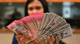 Karyawan memperlihatkan uang pecahan rupiah dan dolar Amerika Serikat (AS) di gerai penukaran mata uang asing Ayu Masagung, Jakarta, Selasa (12/5/2026)
