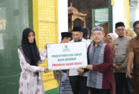 Ketua Baznas Agam Isman Imran menyerahkan zakat, infak dan sedekah kepada mustahik. ANTARA/HO/Baznas Agam
