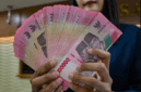 Petugas penukaran uang menunjukkan uang Rupiah di sebuah gerai penukaran mata uang di Jakarta (12/5/2026). Foto: Bay Ismoyo/AFP