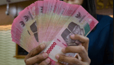 Petugas penukaran uang menunjukkan uang Rupiah di sebuah gerai penukaran mata uang di Jakarta (12/5/2026). Foto: Bay Ismoyo/AFP