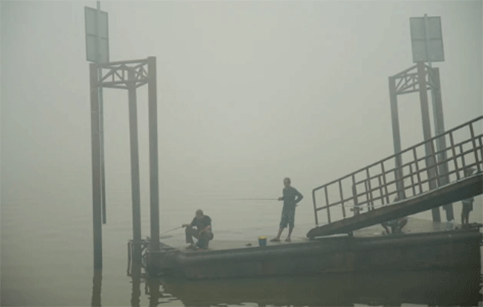 Warga memancing di Sungai Musi saat kabut asap akibat kebakaran hutan menyelimuti daerah tersebut di Palembang, Sumatera Selatan