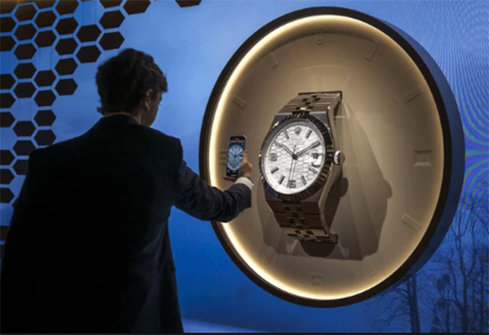 Seorang pria mengambil gambar replika model raksasa dari model baru Rolex penghuni daratan, pada hari pembukaan pameran jam tangan mewah 
