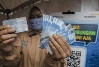 Ilustrasi - Seorang pekerja menunjukkan kartu ATM dan uang saat menerima Bantuan Subsidi Upah (BSU) di halaman PT Perusahaan Industri Ceres, Kabupaten Bandung, Jawa Barat.