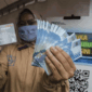 Ilustrasi - Seorang pekerja menunjukkan kartu ATM dan uang saat menerima Bantuan Subsidi Upah (BSU) di halaman PT Perusahaan Industri Ceres, Kabupaten Bandung, Jawa Barat. 